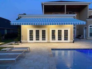 Poolside patio with striped awning and French doors at dusk