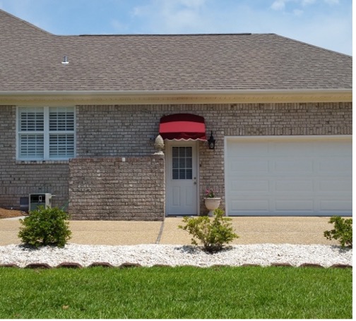 Suburban brick house with garage and red awning.