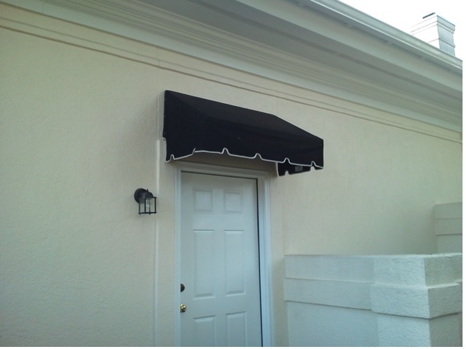 Black awning over white door on house facade.