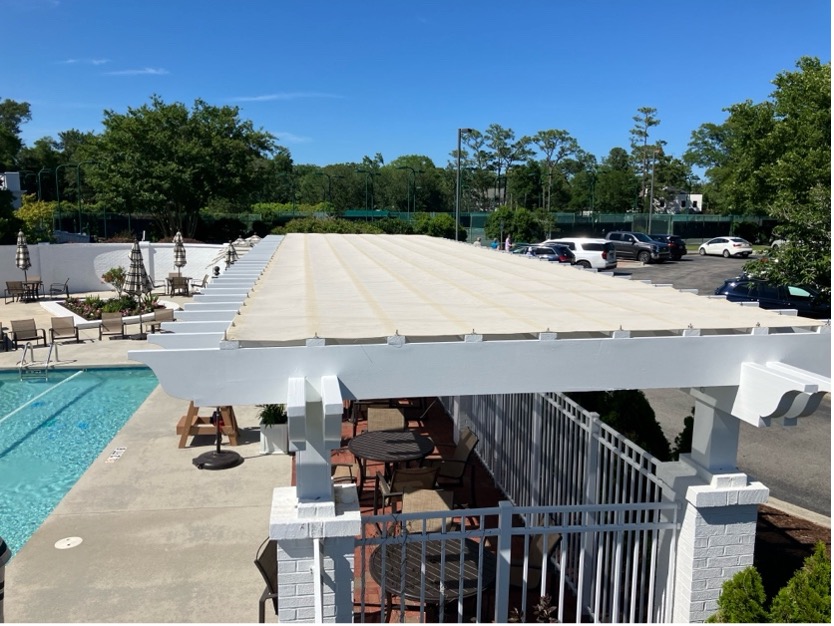 Sunlit poolside patio with retractable awning and seating area.