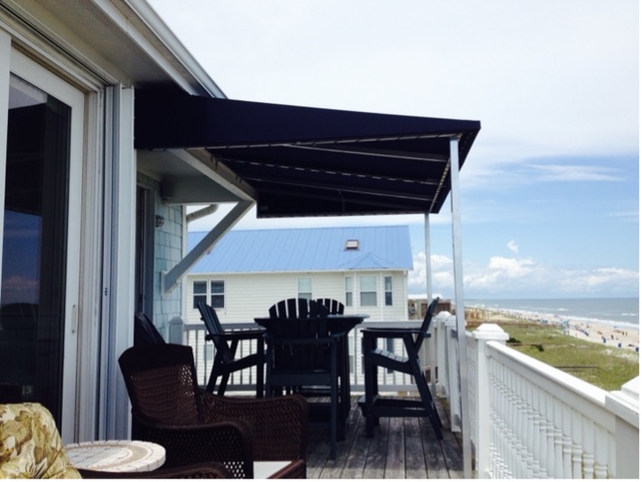 Beach house deck with outdoor furniture overlooking the ocean.