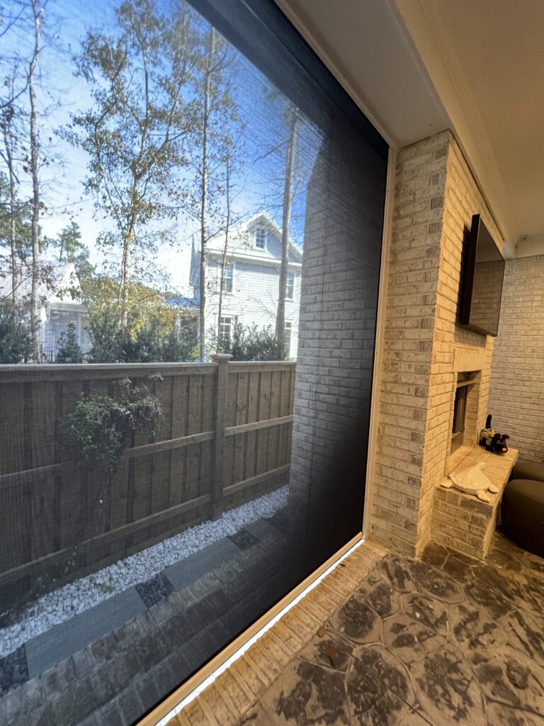 View from sunroom with blinds and brick fireplace.