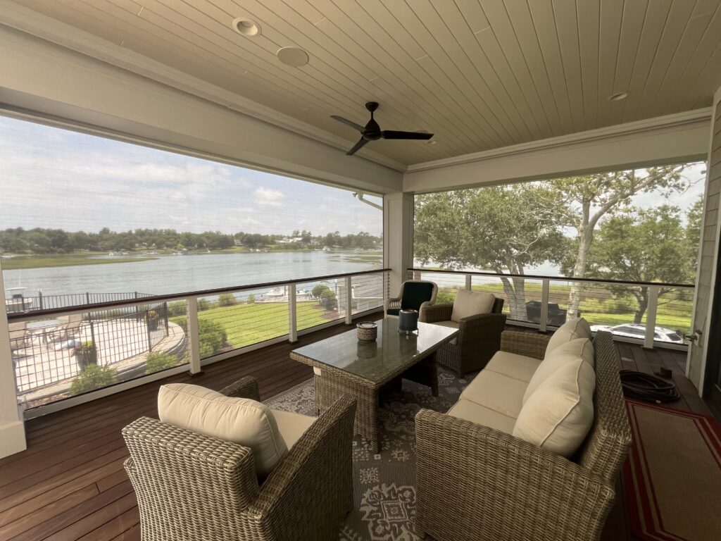 Lake view from screened porch with wicker furniture.