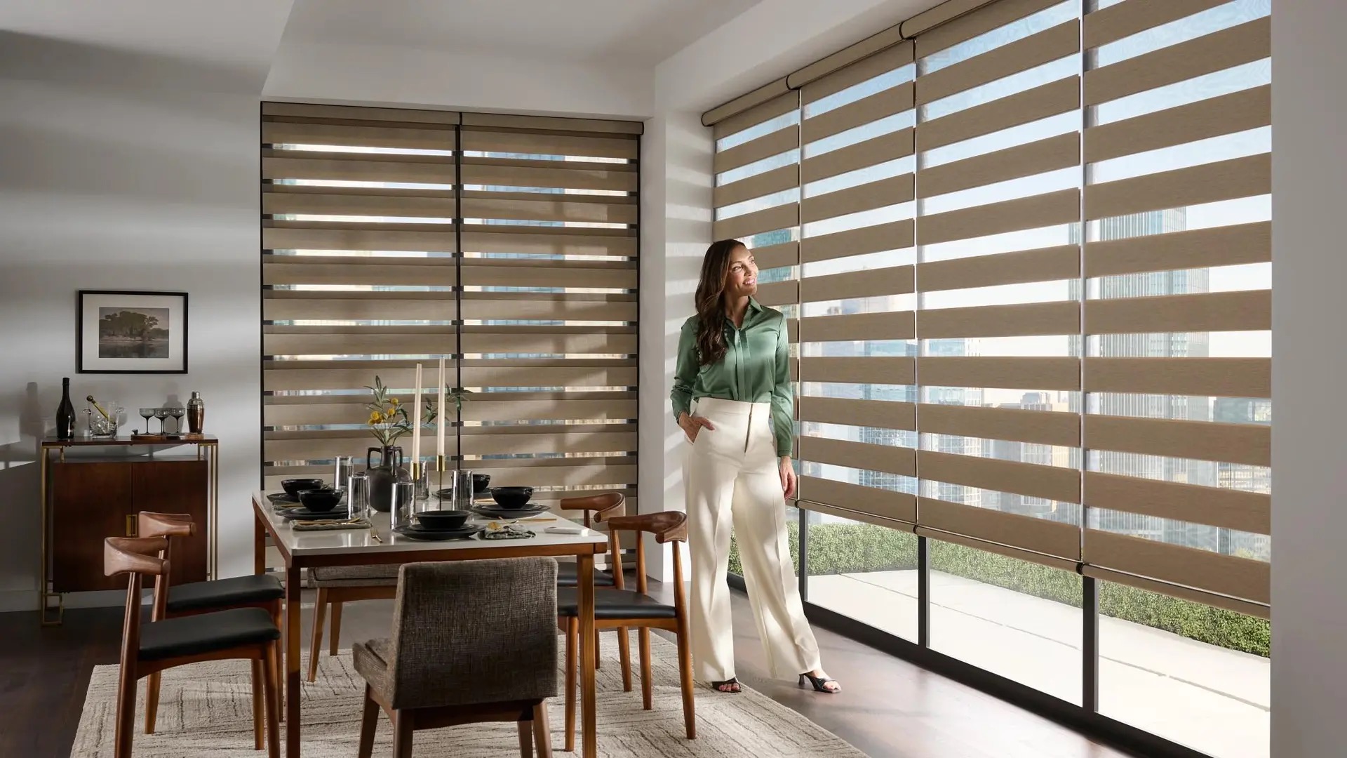 Woman admiring modern dining room interior with window shades.